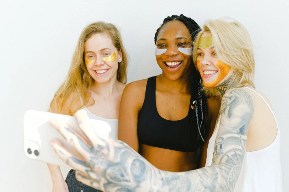  Three smiling women recording themselves on a smartphone.